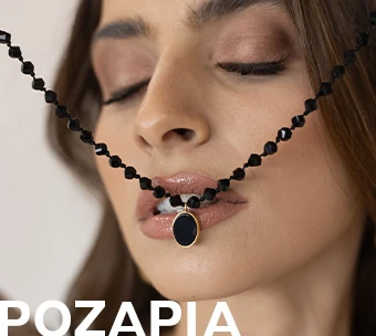 Γυναίκα κρατά μαύρο κολιέ με ματ χάντρες και οβάλ μενταγιόν, ιδανικό για κομψές και μοντέρνες εμφανίσεις.