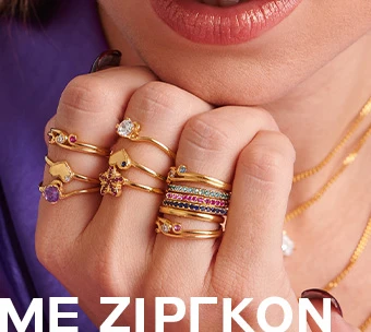 Γυναικείο χέρι στολισμένο με χρυσά δαχτυλίδια, διακοσμημένα με πολύχρωμες πέτρες ζιργκόν, προσφέροντας στυλ και λάμψη για εντυπωσιακές εμφανίσεις.